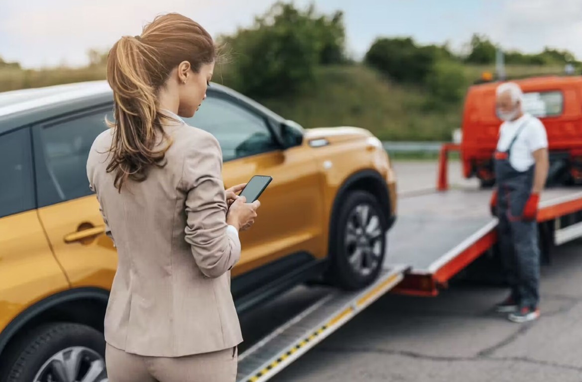 Roadside assistance technician helping a driver next to a flatbed tow truck in Copiague, NY
