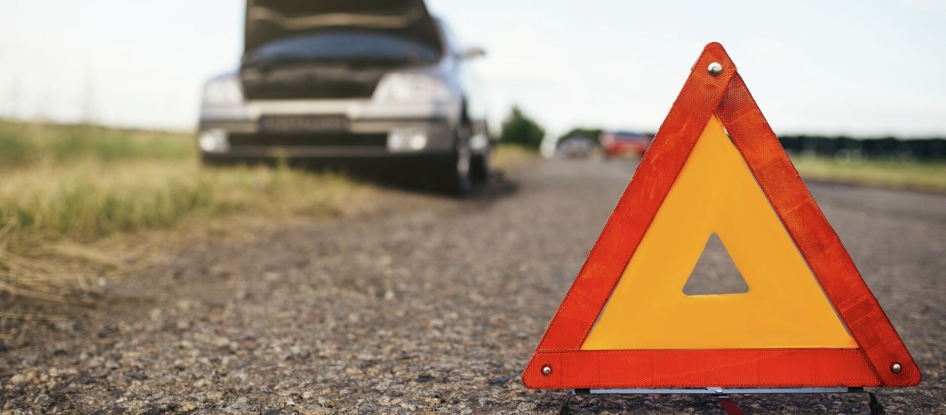 Road emergency warning triangle in front of a broken down vehicle needing roadside assistance in Copiague, NY