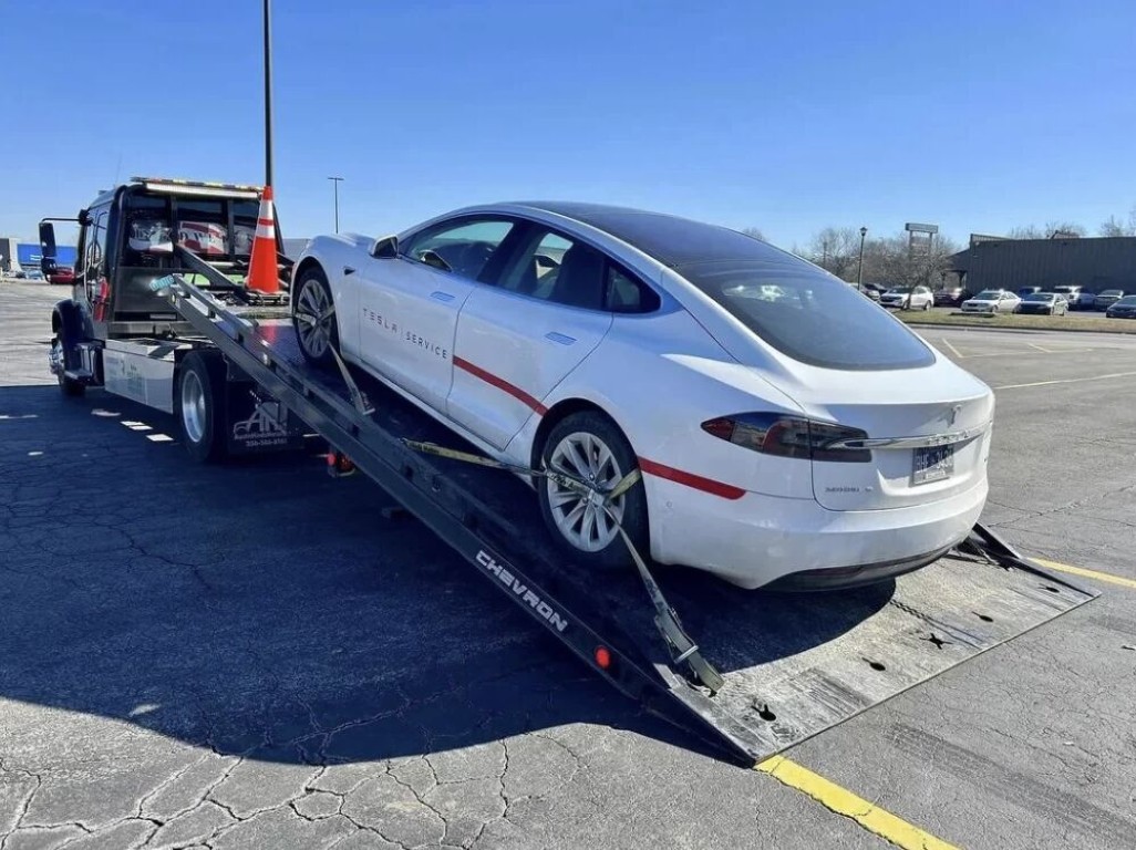 Tesla Model S being loaded onto a Chevron flatbed tow truck for long distance towing in Copiague, NY